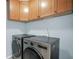 Bright laundry room featuring a modern washer and dryer with wooden cabinets above at 100 Castlebrook Chase, Tyrone, GA 30290