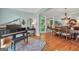 Open-concept living and dining area features a grand piano, hardwood floors, and ample natural light at 100 Castlebrook Chase, Tyrone, GA 30290