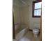 Bathroom with tub, toilet, window, and neutral colored wallpaper at 140 Dixie Ln, Covington, GA 30014