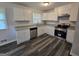 Bright kitchen featuring white cabinets, stainless steel appliances, granite countertops, and stylish wood-look floors at 993 Roosevelt Se Dr, Atlanta, GA 30354