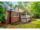 Charming brick home featuring a metal roof, white trim, and a welcoming front porch surrounded by lush landscaping at 301 East Highway 5, Roopville, GA 30170