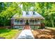 Charming exterior with metal roof, brick accents, dormers, and a welcoming porch, surrounded by lush greenery at 301 East Highway 5, Roopville, GA 30170