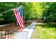 View of a well-maintained yard with an American flag, a paved walkway, and mature trees providing shade and privacy at 301 East Highway 5, Roopville, GA 30170