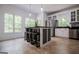 Bright, open kitchen with central island with seating, stainless appliances, and large windows at 301 East Highway 5, Roopville, GA 30170
