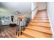 Hardwood staircase connecting to a living room with a ceiling fan, artwork and comfortable seating with an ottoman at 301 East Highway 5, Roopville, GA 30170