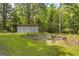 Beautiful backyard featuring a storage shed, raised garden beds, and lush green grass surrounded by mature trees at 2164 Old Rex Morrow Rd, Morrow, GA 30260