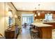 View of kitchen with pendant lighting, granite countertops, wood cabinets and floors, and view into dining area at 148 Lakeside Dr, Peachtree City, GA 30269