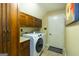 Laundry room with white washer and dryer, wood cabinets, and granite countertop at 148 Lakeside Dr, Peachtree City, GA 30269