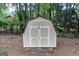 A close-up of the backyard shed, featuring neutral paint, double doors, and a lattice foundation for ventilation at 148 Lakeside Dr, Peachtree City, GA 30269
