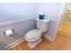 Traditional white toilet and white walls, with hardwood floors and gold accents in a neat bathroom at 148 Lakeside Dr, Peachtree City, GA 30269