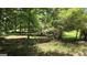 Image shows the land behind the house, filled with trees and grassy spots at 1448 Se Hillside Place, Conyers, GA 30094
