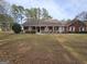 Classic red brick house featuring a charming covered front porch and manicured lawn with mature trees at 164 Turner Creek Dr, Hampton, GA 30228