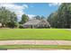 Exterior view of a single-story home with a sprawling lawn, stone accents, and mature trees at 320 Silverbell Ln, Sharpsburg, GA 30277