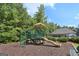 Community playground with slide, climbing bars, and playhouse, surrounded by lush trees and landscaping at 320 Silverbell Ln, Sharpsburg, GA 30277