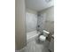 Bathroom showcasing a tub with marble tile, updated fixtures, and a modern toilet at 9107 Morris Sw Dr, Covington, GA 30014