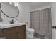 Neutral bathroom features a dark vanity, round mirror, and a shower with a patterned curtain at 425 Birkdale Dr, Fayetteville, GA 30215