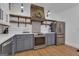 Stylish kitchen with a custom wooden range hood, gray cabinets, open shelving, and modern stainless steel appliances at 425 Birkdale Dr, Fayetteville, GA 30215