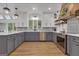 Bright kitchen featuring gray cabinets, a stainless steel dishwasher, a large quartz countertop island, and a custom range hood at 425 Birkdale Dr, Fayetteville, GA 30215