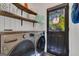 Laundry room with stainless steel washer and dryer, open shelving, and an exterior door with a view to the outdoors at 425 Birkdale Dr, Fayetteville, GA 30215