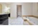 A marble-trimmed soaking tub with a view toward the sink and toilet area at 123 Eva Ln, Stockbridge, GA 30281
