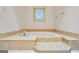A jetted tub with marble-style trim and a window in the bathroom at 123 Eva Ln, Stockbridge, GA 30281