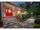 Welcoming front entrance featuring a red door, stone steps, and a charming stone walkway, all surrounded by lush greenery at 123 Eva Ln, Stockbridge, GA 30281