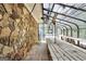 Interior view of the greenhouse showing stone wall and glass roof, with a long wooden table at 123 Eva Ln, Stockbridge, GA 30281