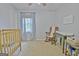 Bedroom features a vintage rocking chair, changing table, and view of backyard from the window at 345 Summer Pl, Peachtree City, GA 30269