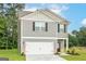 View of a two-story home with gray siding and a two-car garage, set against a backdrop of trees at 282 Limestone Circle, Conyers, GA 30013
