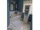 Bright bathroom featuring a soaking tub, a cabinet and a window, all with white tiled floors at 1524 Queen Elizabeth Dr, Locust Grove, GA 30248