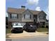 Two-story home with brick and gray siding, green shutters, two cars in driveway, and a small front lawn at 1524 Queen Elizabeth Dr, Locust Grove, GA 30248