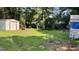 Large backyard with a storage shed surrounded by grass and greenery at 8436 Magnolia Dr, Jonesboro, GA 30238