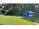 Spacious backyard featuring a blue tarp-covered structure amidst mature trees and lush green grass at 8436 Magnolia Dr, Jonesboro, GA 30238