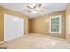 Cozy bedroom with neutral carpet, ceiling fan, and white closet doors; plenty of natural light from the window at 10044 Point View Dr, Jonesboro, GA 30238