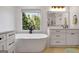 Bright bathroom featuring a modern tub with black fixtures, a window view, and a stylish white vanity at 551 Lees Mill Rd, Fayetteville, GA 30214