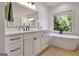 Bright bathroom featuring white cabinets, quartz counters, soaking tub, and a large window at 551 Lees Mill Rd, Fayetteville, GA 30214
