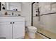 Modern bathroom with white vanity, black hardware, glass-enclosed shower, and wood-look tile at 551 Lees Mill Rd, Fayetteville, GA 30214