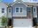 Two-story townhome features a two-car garage, blue shingle siding, and brick accents at 332 Sinclair Ct # 77, Mcdonough, GA 30253