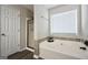 Bright bathroom featuring a soaking tub, separate glass shower, and a large window at 85 Eastwood Frst, Covington, GA 30014
