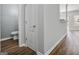 Hallway with hardwood floors and a view of the powder room and open-concept living area at 2203 Hyssop Way, Buford, GA 30519
