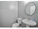 Neutral powder room featuring modern fixtures, toilet, sink, and round mirror at 2203 Hyssop Way, Buford, GA 30519