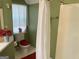 Bathroom with green walls featuring a shower with curtain, toilet with red seat, and small window at 3232 Deer Pause Ln, Decatur, GA 30034