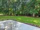 Lush green backyard featuring a concrete patio with outdoor seating and a serene wooded backdrop at 2866 Rosecommons Dr, Hampton, GA 30228