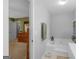 Bright bathroom with a large soaking tub and a view into an adjacent bedroom featuring a dresser and mirror at 2866 Rosecommons Dr, Hampton, GA 30228