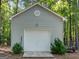 Detached garage with a white garage door, side door, and surrounded by lush trees and landscaping at 2866 Rosecommons Dr, Hampton, GA 30228