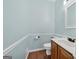Powder room with light blue walls, wood floors, and white fixtures at 11 Chad Ct, Mcdonough, GA 30253