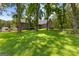 Large backyard with lush green grass, mature trees and home with deck at 152 Bear Creek Rd, Moreland, GA 30259