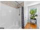 Bathroom shower with tile accent wall, wood floors, and a sunny window with plants nearby at 152 Bear Creek Rd, Moreland, GA 30259