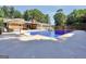 In-ground pool surrounded by a large patio, complete with an umbrella, with a brick house in the background at 234 Crumbley Rd, Mcdonough, GA 30252