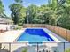 Fenced in swimming pool with crystal-clear water, surrounded by mature trees, with a wooden fence at 234 Crumbley Rd, Mcdonough, GA 30252